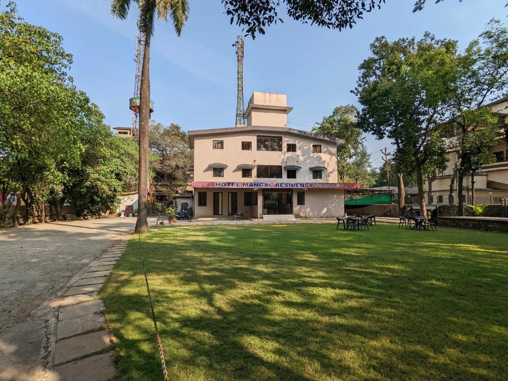 a building with a lawn in front of it at Hotel Mangal Residency Lonavala - Best Hotel in Lonavala in Lonavala