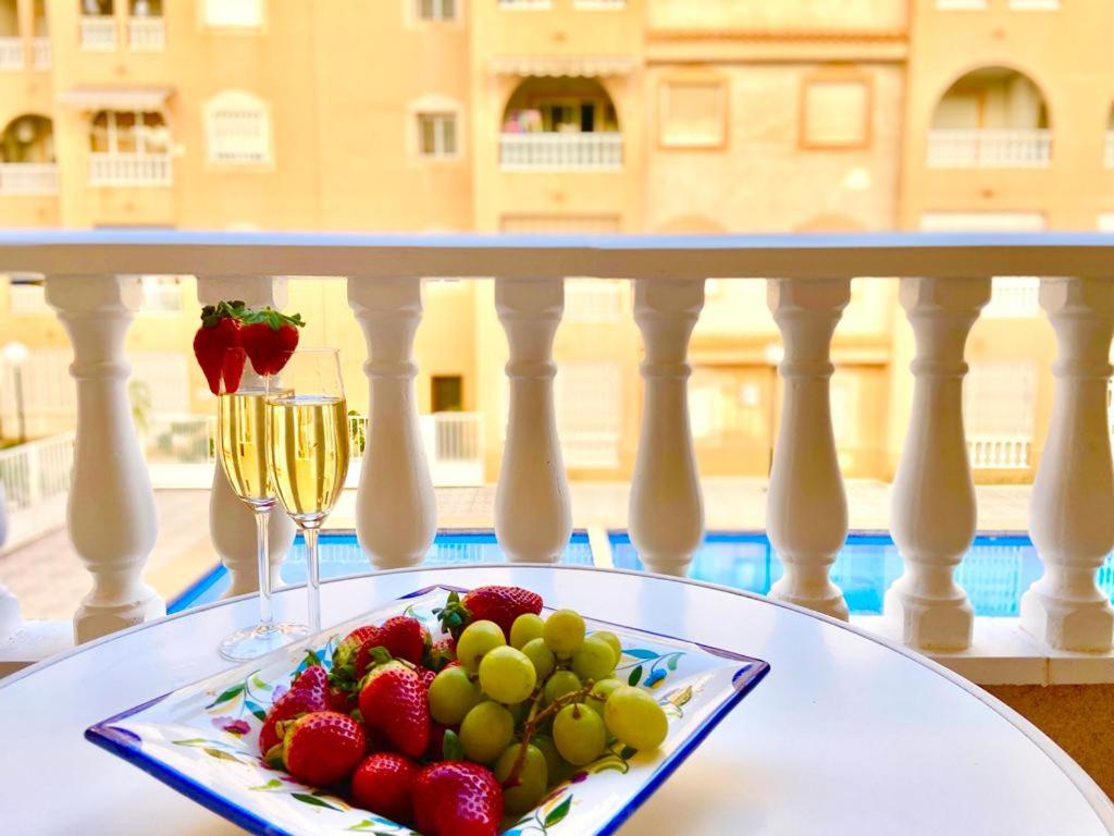 a plate of fruit on a table with a glass of wine at Apartamento Mimosa in Torrevieja
