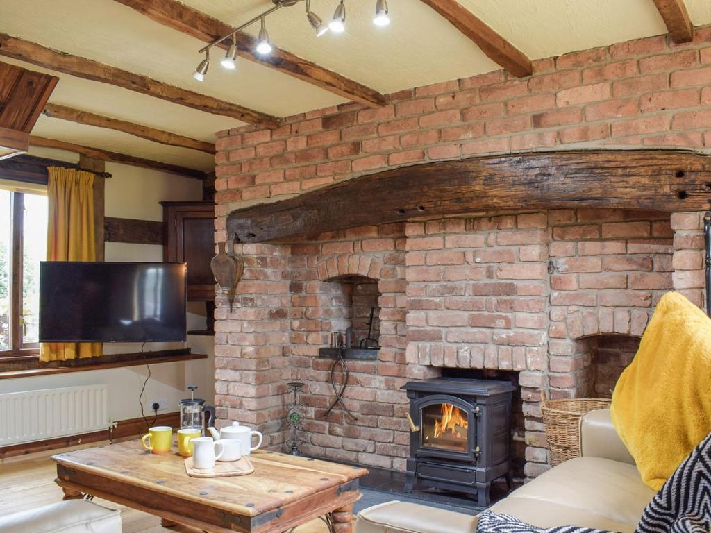 a living room with a brick wall with a fireplace at Ysgubor Hir in Trefeglwys