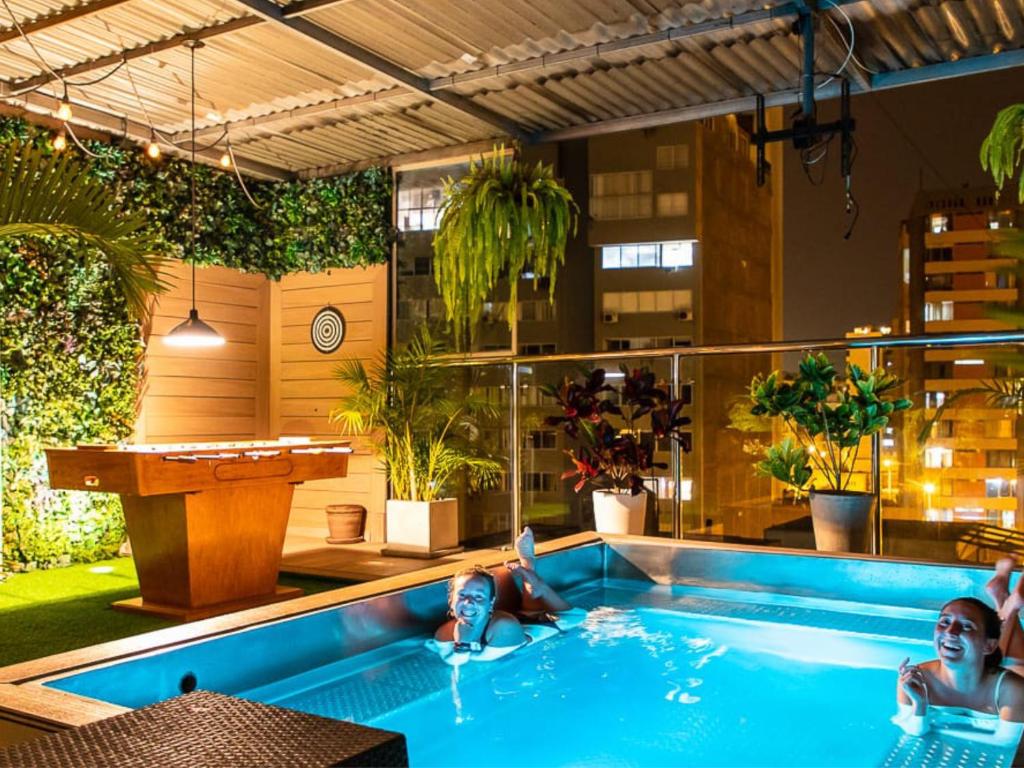two people laying in a swimming pool in a building at Alpes Lima Kennedy Hostel in Lima