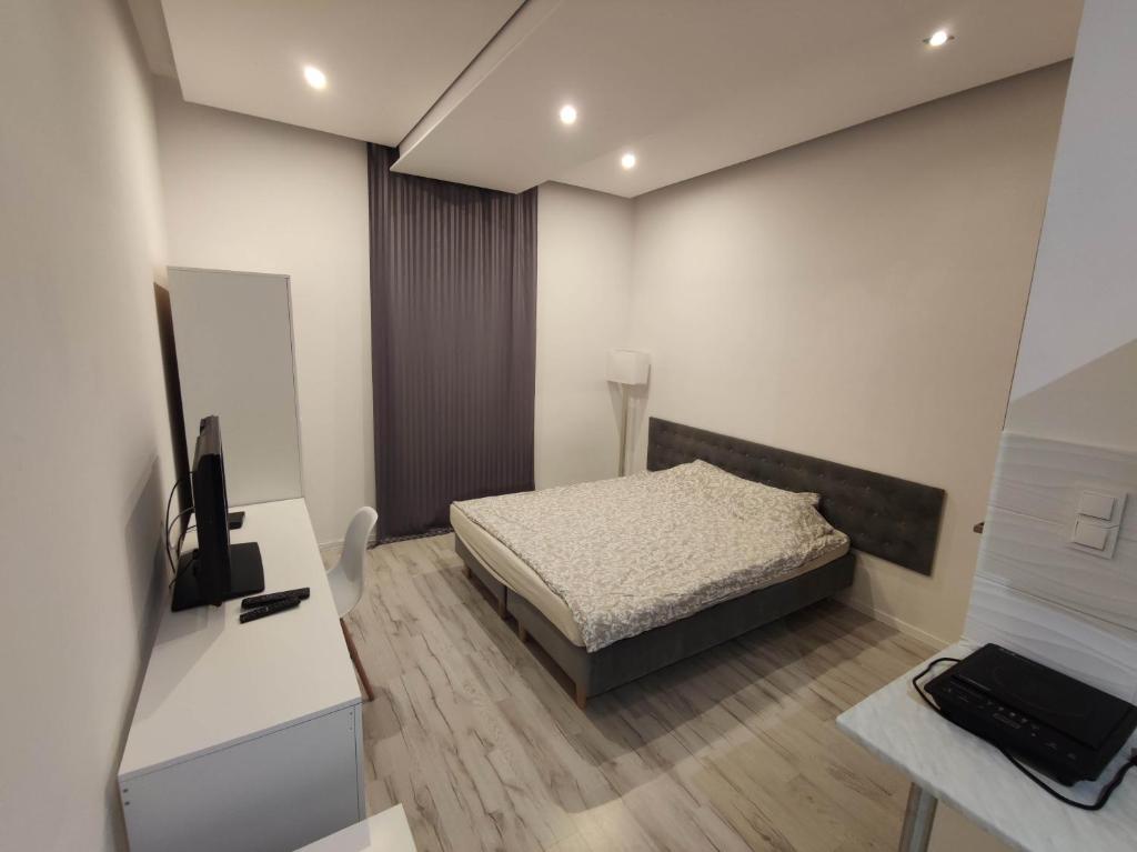 Dormitorio con cama, escritorio y TV en Micadas Apartamenty en Piaseczno