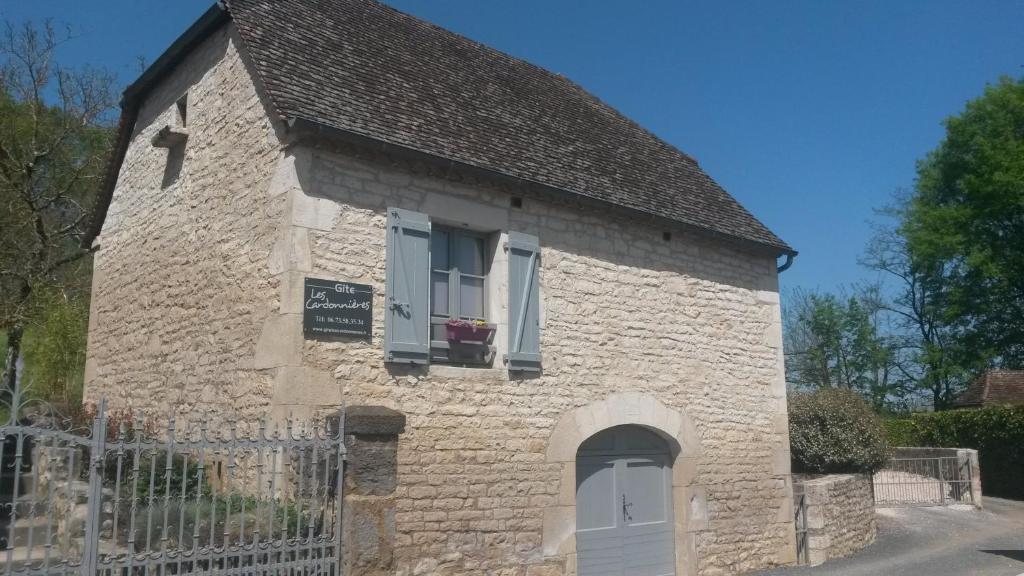 CarennacにあるGîte des Cardonnièresの窓と扉のある小さな石造りの建物