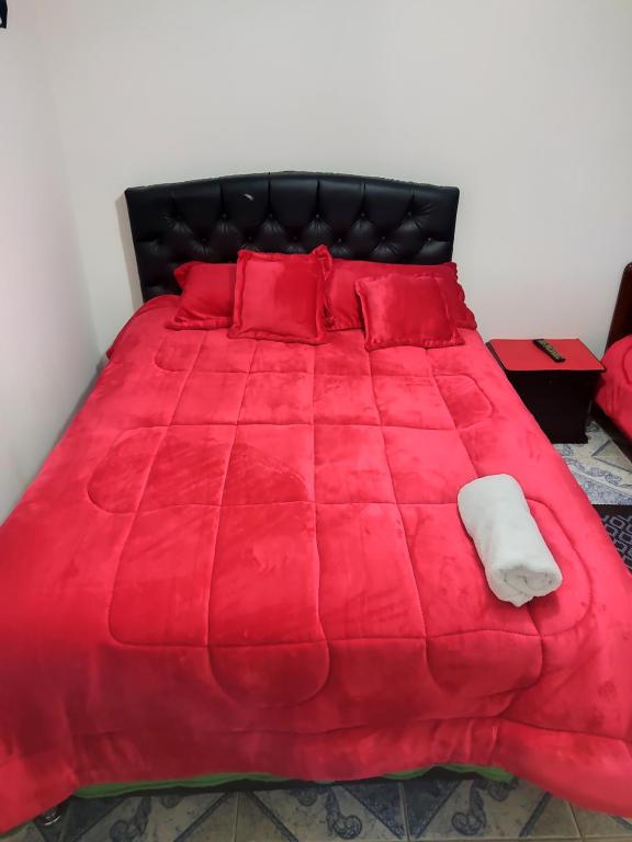 1 cama roja con edredón rojo y almohadas rojas en La Cachaca en Bogotá