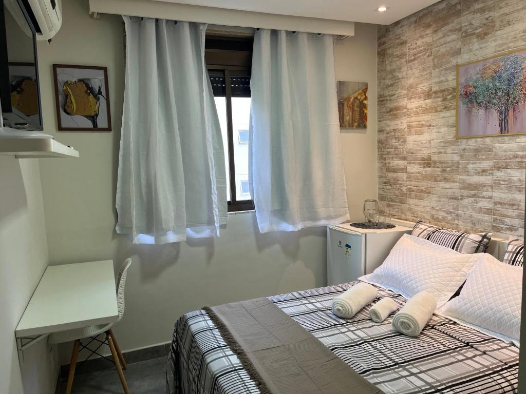 a bedroom with a bed with two pillows and a window at STUDIOS CORACAO EUCARISTICO in Belo Horizonte