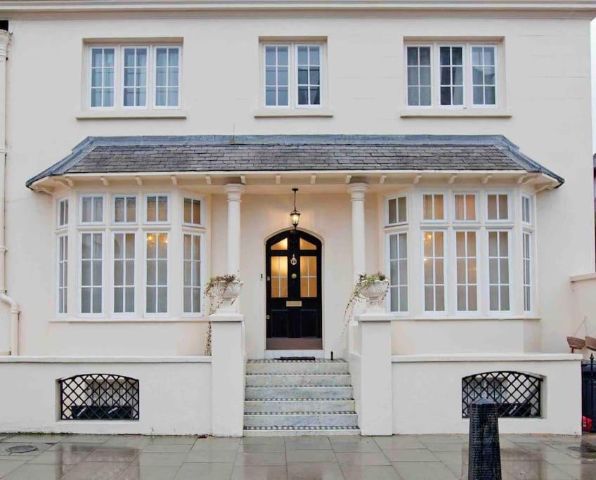 a white house with a black door and stairs at Beautiful 4 Bed House by Regents Park in London