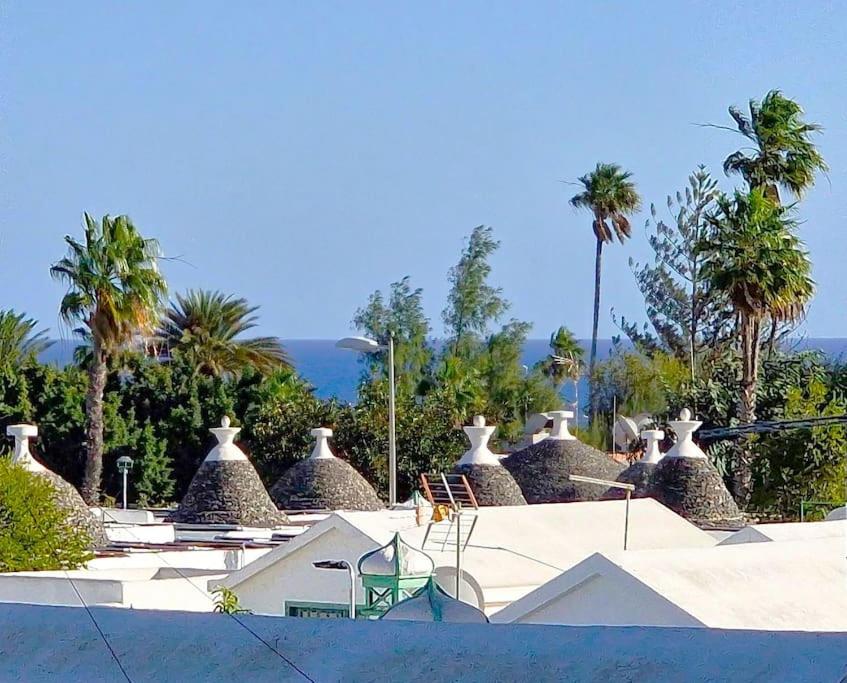 a view of a resort with palm trees and roofs at Your Luxurious Home Near The Dunes! in Playa del Ingles