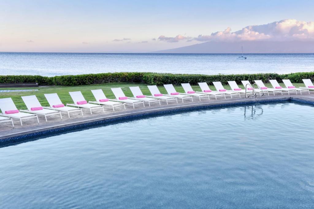 - une piscine avec des chaises longues et l'océan dans l'établissement Royal Lahaina Resort & Bungalows, à Lahaina