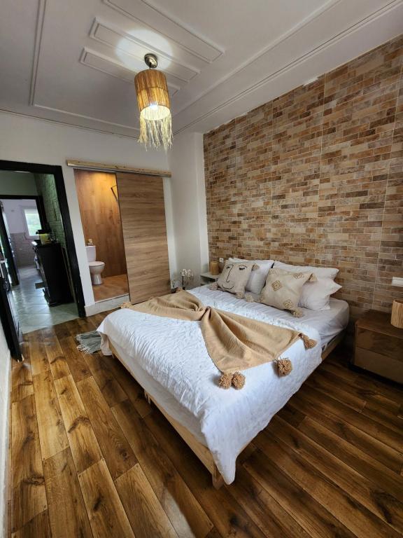 um quarto com uma cama grande e uma parede de tijolos em FamilyConfort Saidia em Saïdia
