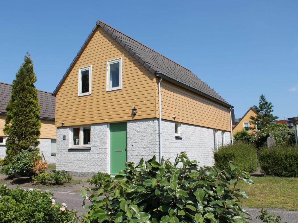 a house with a green door in a yard at Holiday Home in Quiet Park for Families in Wemeldinge