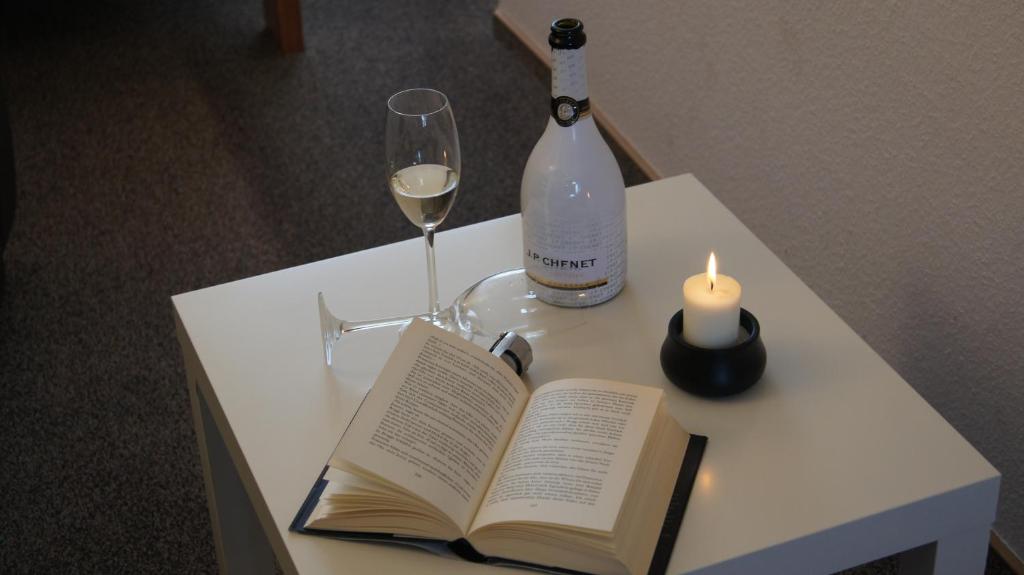 einen Tisch mit einem Buch, eine Flasche Wein und eine Kerze in der Unterkunft Ferienapartments Sonnenhof in Waren (Müritz)