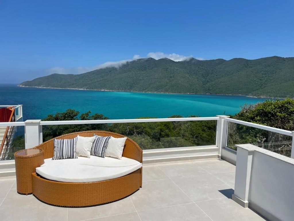 una silla de mimbre en un balcón con vistas al agua en Casa aconchegante Pontal do Atalaia Vista Mar, en Arraial do Cabo