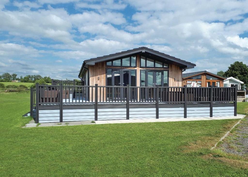 a wooden house with a fence in a field at Barlings Country Park in Langworth