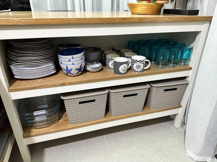 a shelf with plates and cups and bowls and baskets at Seafront OnCall - private jacuzzi with 4 cozy bedrooms in San Juan