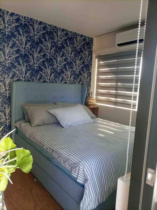 a bed in a bedroom with a blue wall at Seafront OnCall - private jacuzzi with 4 cozy bedrooms in San Juan