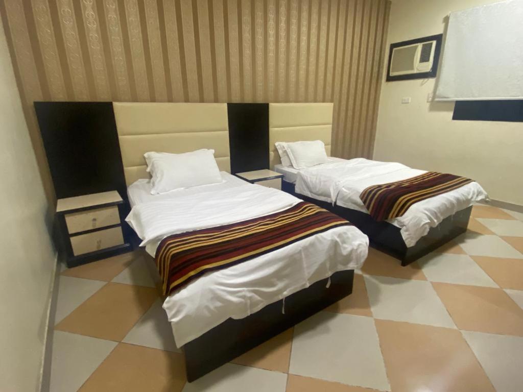 two beds in a room with a tiled floor at نزيل للشقق المفروشة in Taif