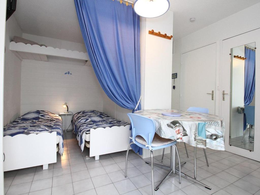 une chambre avec deux lits, une table et des chaises dans l'établissement Charmant T1 avec Loggia au Sud, Calme, Près Centre-Ville, Garage, Bien Équipé - FR-1-553-58, à Balaruc-les-Bains