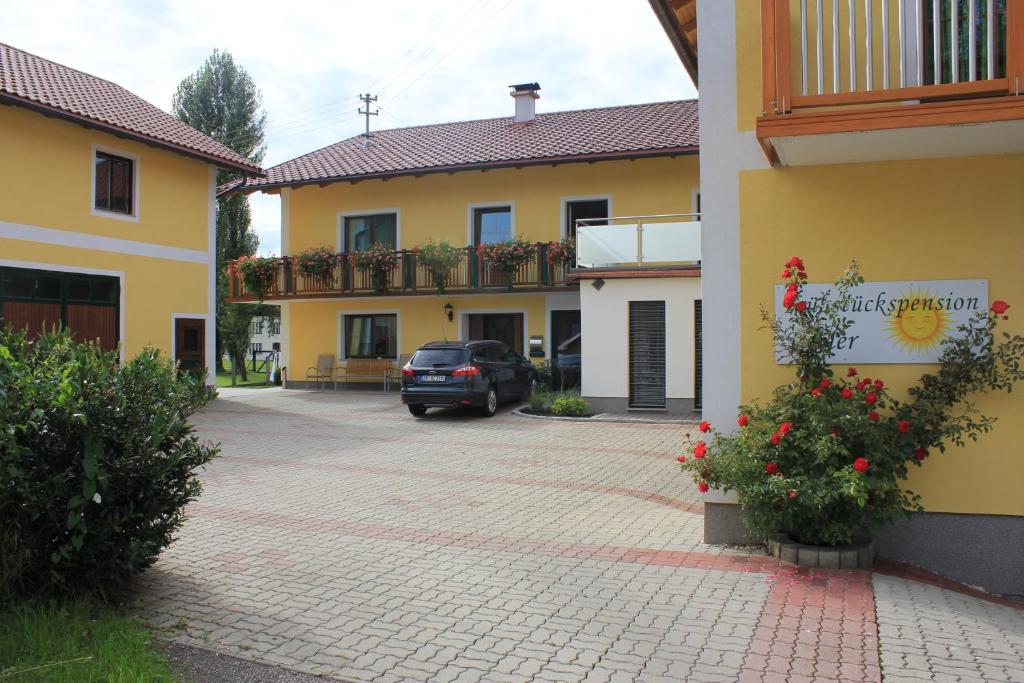 ein Auto, das auf einem Parkplatz neben einem Gebäude parkt in der Unterkunft Frühstückspension Kibler in Sankt Georgen im Attergau