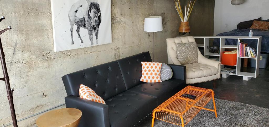 ein Wohnzimmer mit einem schwarzen Sofa und einem Stuhl in der Unterkunft Modern lofty studio in Midtown / Charming Old SW in Reno