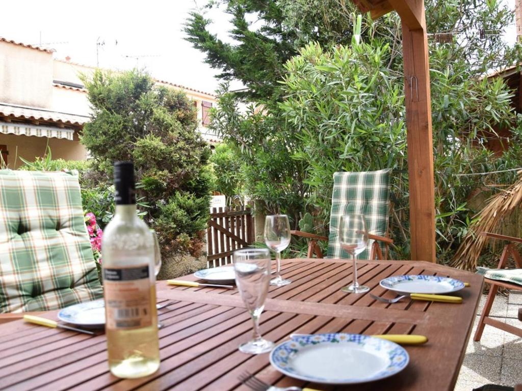 - une table en bois avec une bouteille de vin et des verres dans l'établissement Maison de vacances à Gruissan - 5 couchages, piscine, proche mer et commerces - FR-1-229-816, à Gruissan