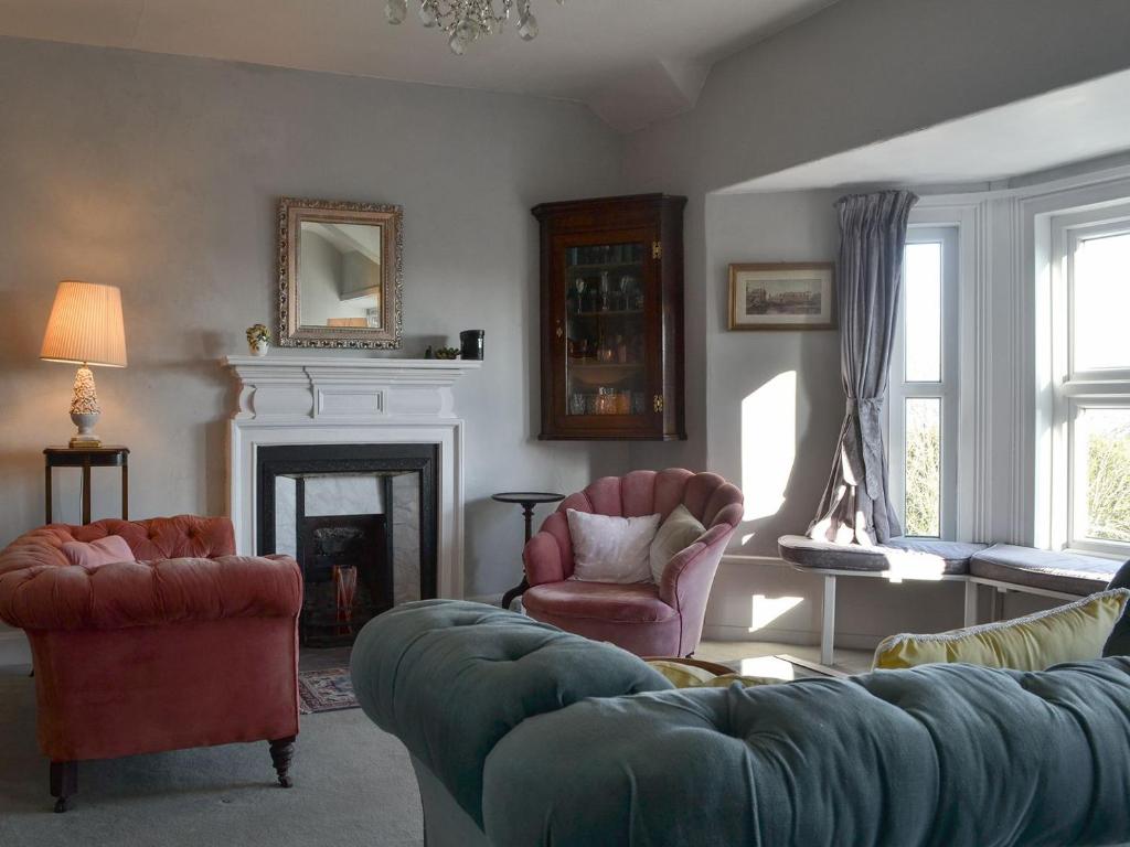 uma sala de estar com um sofá e cadeiras e uma lareira em Gaerwen em Criccieth