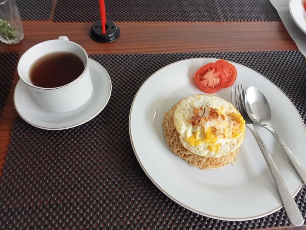 un piatto con una tazza di caffè e un prodotto da forno di Guest House d Valeri a Labuan Bajo