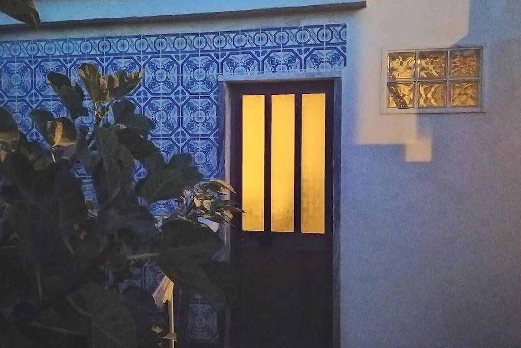 a black door with a yellow window and a plant at Ginjals 67 in Almargem do Bispo