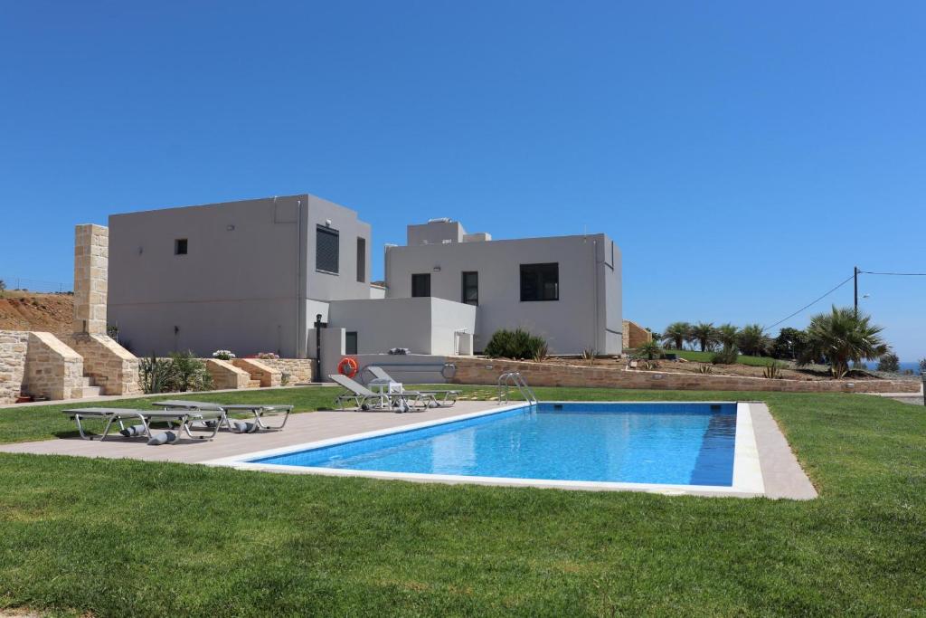 a villa with a swimming pool in front of a house at Triopetra View 1 in Triopetra