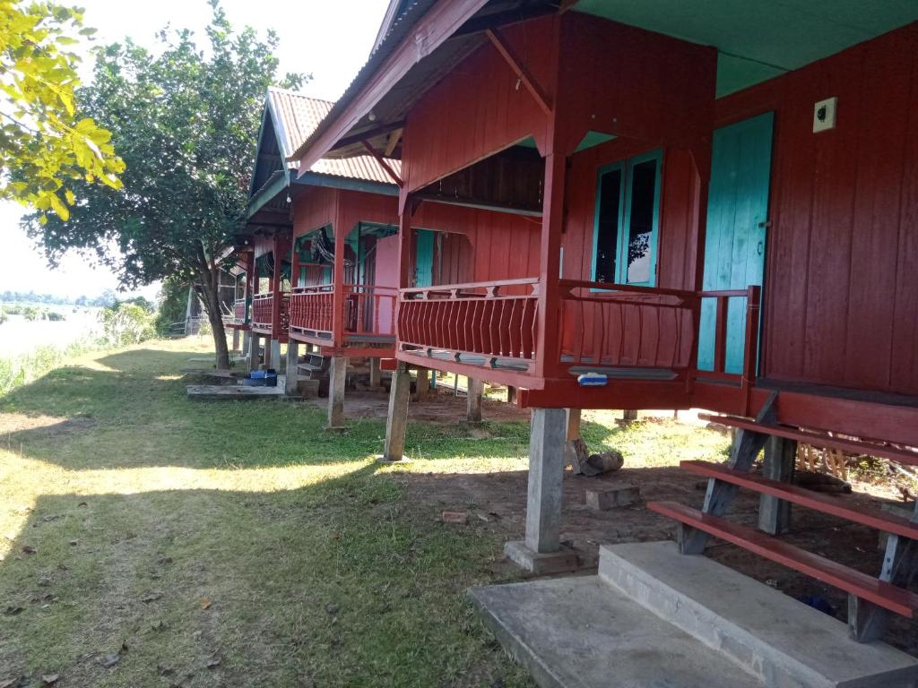 Une rangée de maisons rouges assises sur l'herbe dans l'établissement Mr. Phaos Riverview Guesthouse & Restaurant, à Don Det