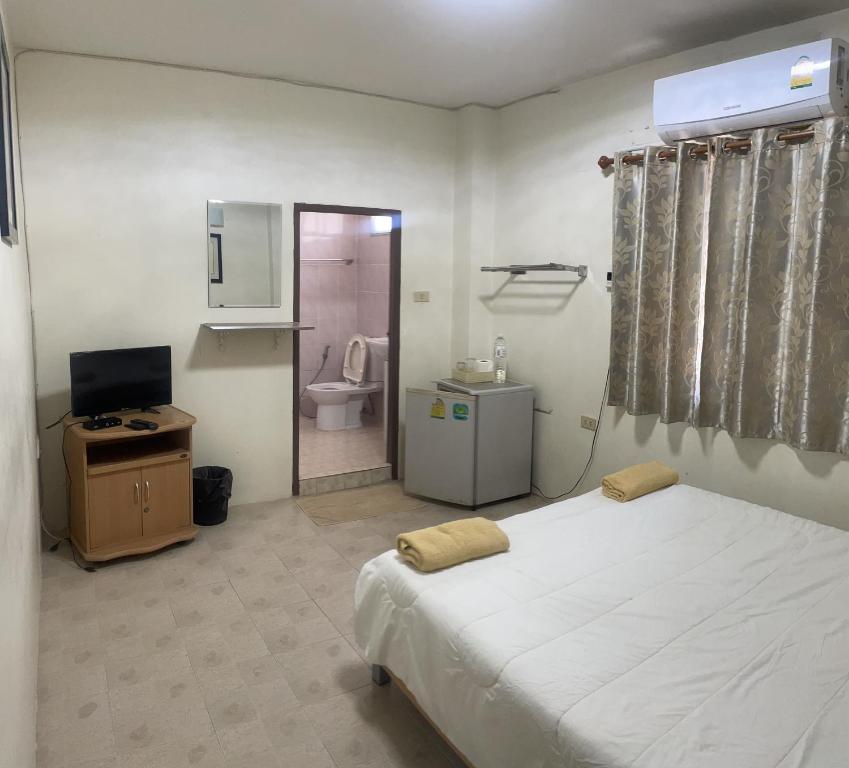 a bedroom with a bed and a television and a bathroom at TK Guesthouse in Cha Am
