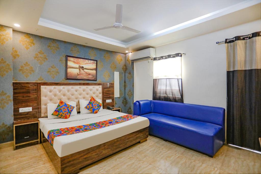 a bedroom with a bed and a blue couch at FabHotel Joy Stick, Sector 11 Noida in Indirapuram