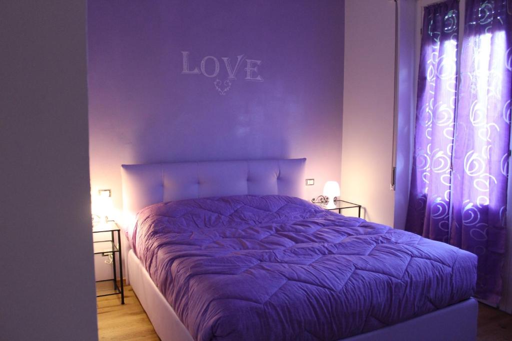 a bedroom with a purple bed with the word love on the wall at Rooms Of Love in Pavia