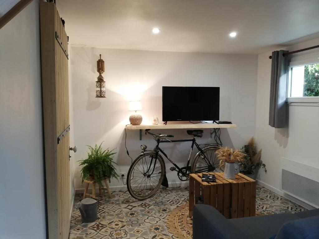 a bike parked in a room with a desk with a television at Martine à la Ferme in Arrest