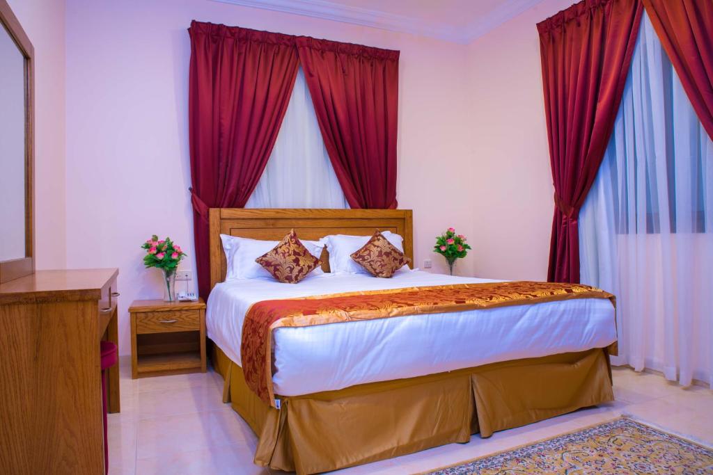 1 dormitorio con 1 cama grande y cortinas rojas en سارا للشقق الفندقية Sara Furnished Apartments en Al Khobar