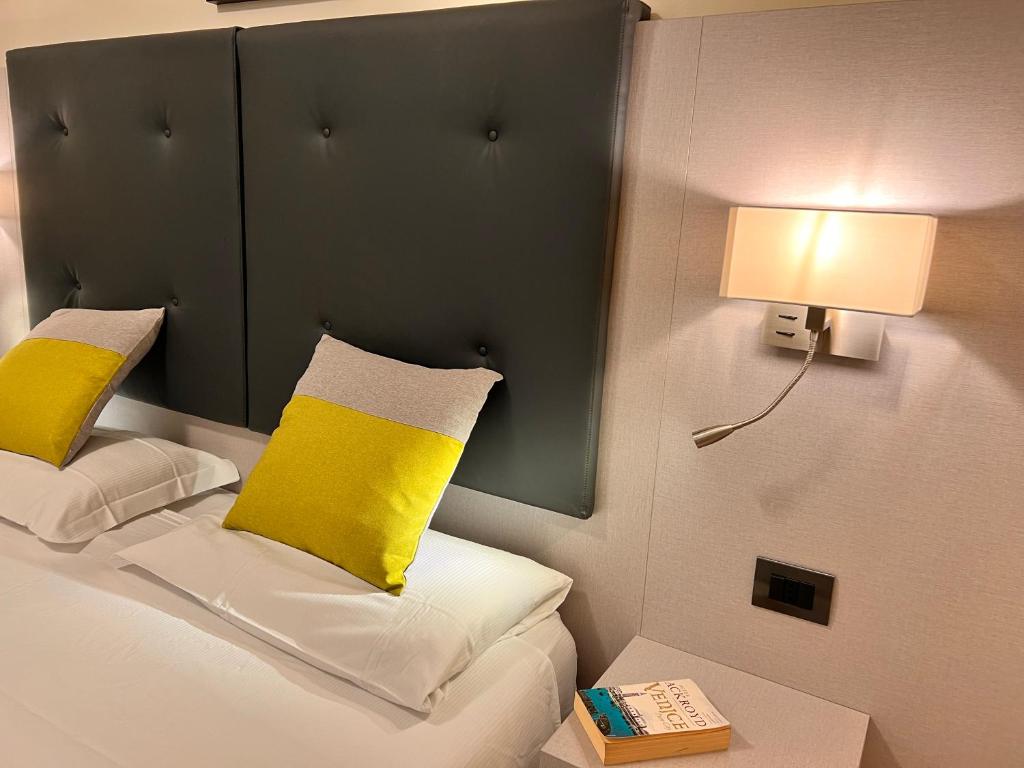 um quarto com uma cama com almofadas amarelas e um candeeiro em Hotel Aurora em Mestre