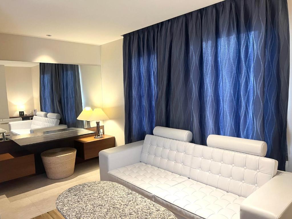 a living room with a white couch and blue curtains at Hotel Ange in Fukuyama