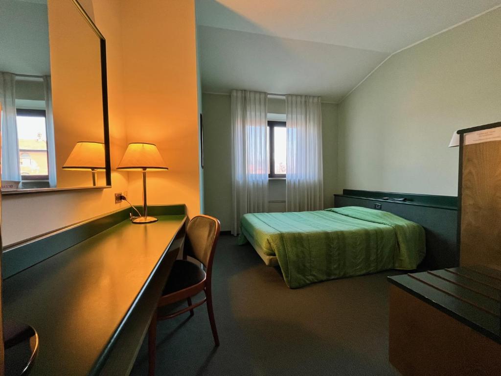 a hotel room with a bed and a desk with a lamp at Hotel La Goletta in Binasco