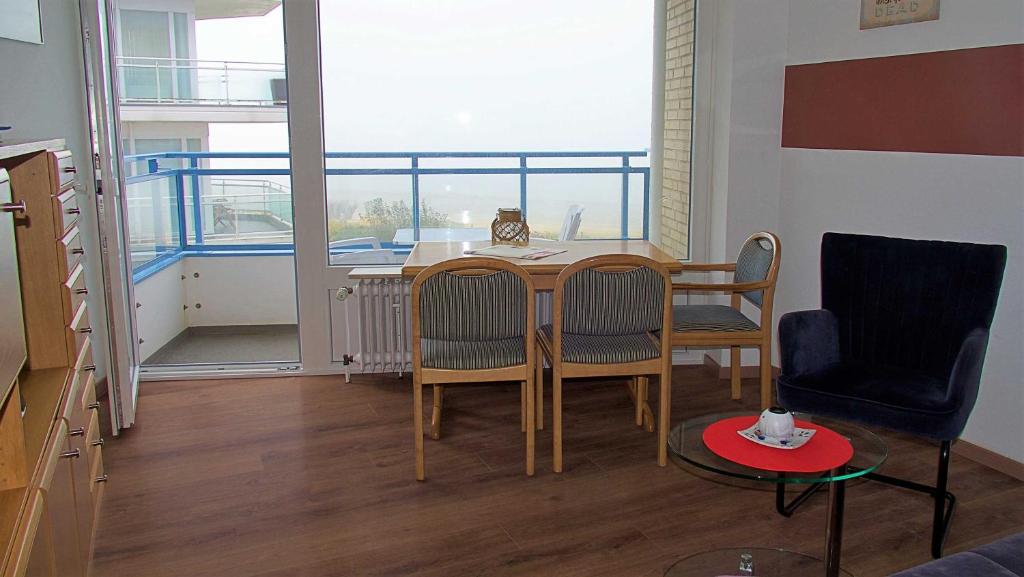a living room with a table and chairs and a balcony at Haus Seehütte Seehütte Haus 2 Wohnung 103 in Cuxhaven