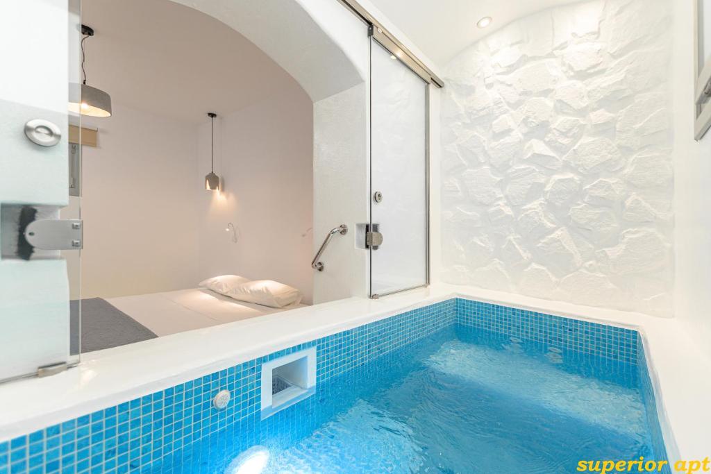 ein Badezimmer mit einer blau gefliesten Badewanne mit Dusche in der Unterkunft Aphrodite Luxury Apartments in Agios Prokopios