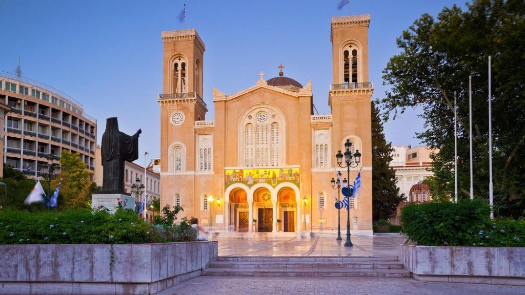 un grande edificio con una statua davanti di Ciel Suites Athens ad Atene