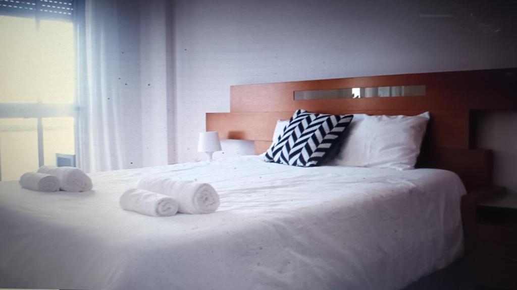 ein Schlafzimmer mit einem weißen Bett und Handtüchern darauf in der Unterkunft GG Massamá Rooms in Queluz