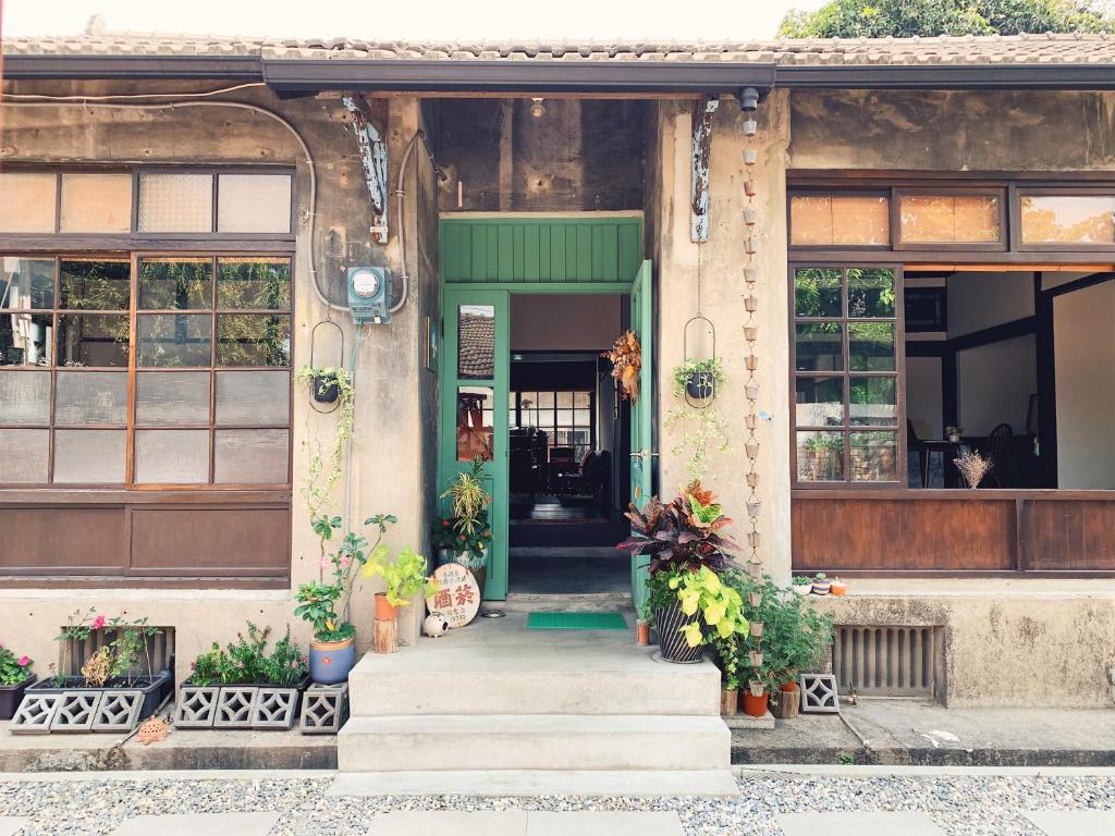 eine grüne Tür auf einem Gebäude mit Pflanzen in der Unterkunft 眷待期休憩所眷村民宿 in Kaohsiung