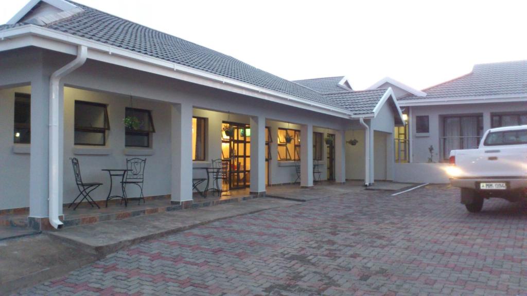 a white house with a car parked in front of it at Tribute Guest House Matala in Maseru