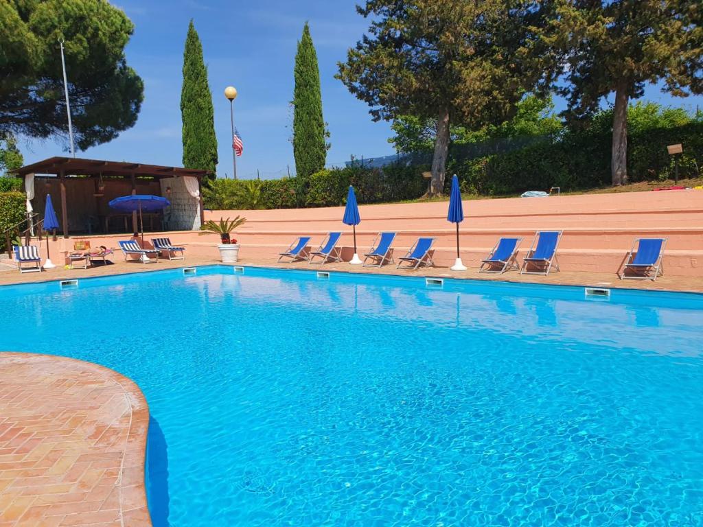 una gran piscina con sillas y sombrillas azules en Toscana Holiday Village, en Montopoli in Val dʼArno