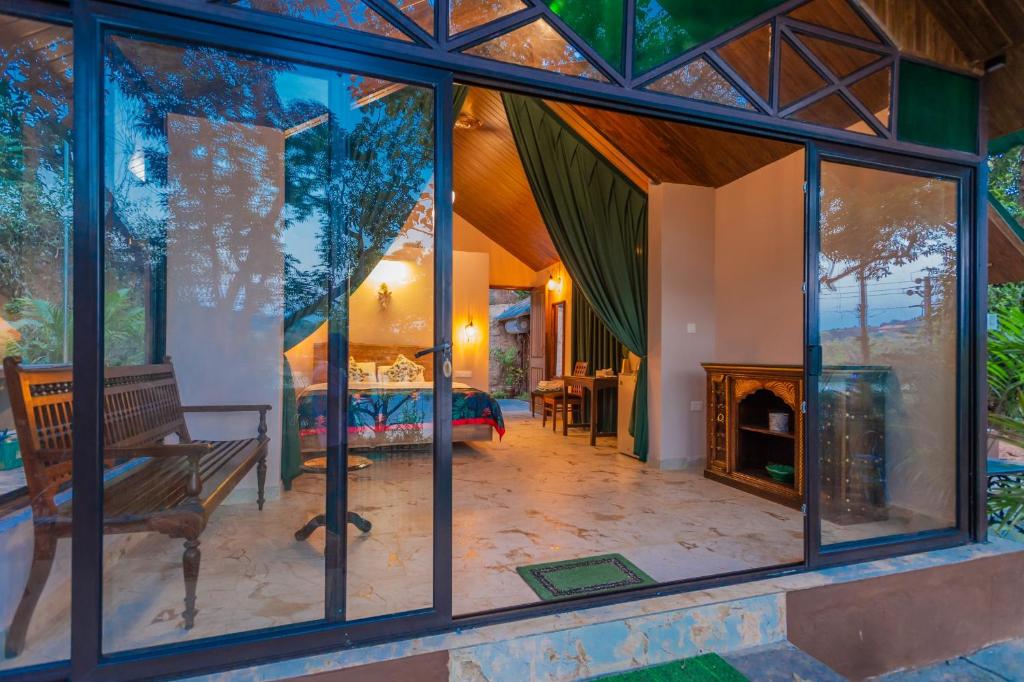 uma sala de estar com janelas de vidro e uma lareira em Nirvana Hill Resort em Curtorim