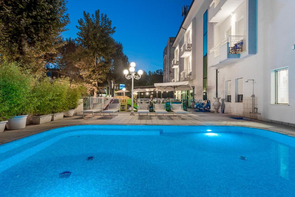 ein großer blauer Pool neben einem Gebäude in der Unterkunft Hotel Milano in Cesenatico