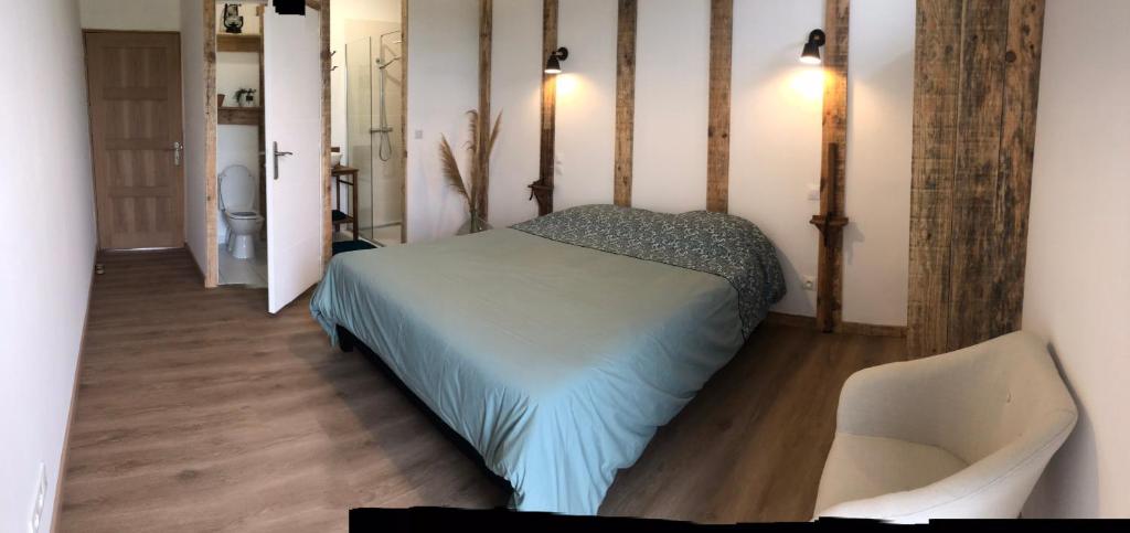 a bedroom with a bed and a chair at Chambres d’hôtes Arremounon in Lamothe