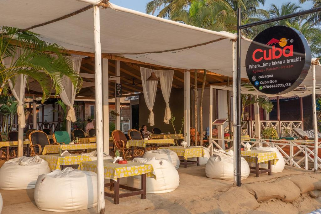 un restaurante con mesas y sillas amarillas y blancas en Cuba Patnem, en Patnem