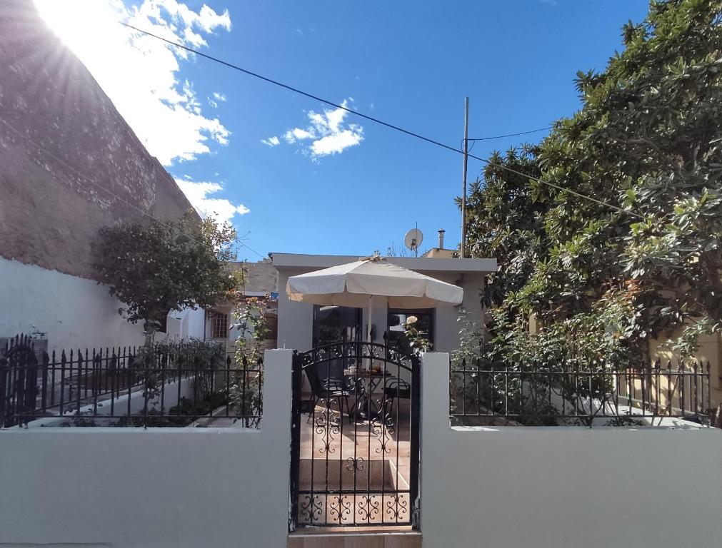 a white fence with an umbrella in front of a house at Irini's Home - Pitsidia in Pitsidia