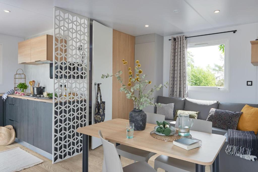 a living room with a table and a kitchen at Camping LES PEUPLIERS in Hyères