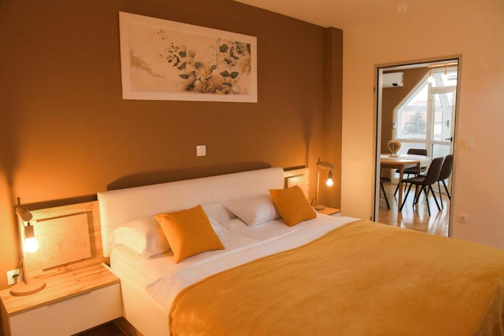 1 dormitorio con 1 cama grande con almohadas de color naranja en Miadora apartments - Apartma Bela štorklja en Moravske-Toplice